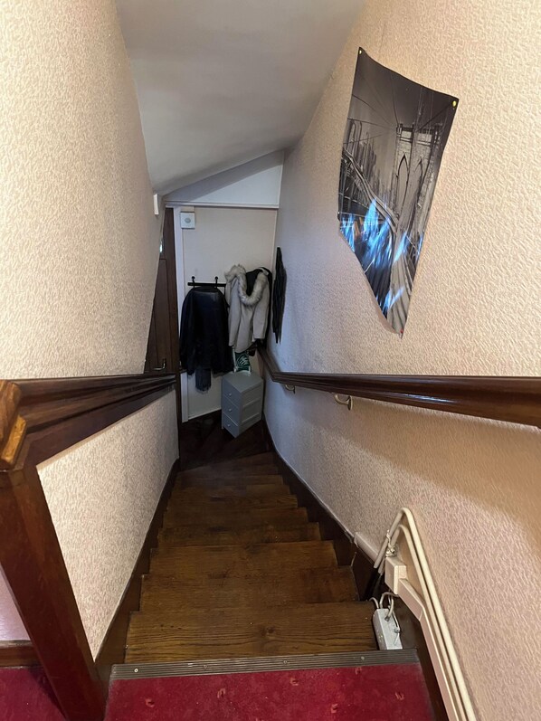 A narrow staircase with wooden handrails and a red carpet at the bottom. - Bed and breakfast USA (Mayenne)