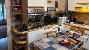 A compact kitchen with a microwave, toaster, and a small refrigerator. There is a dining table with a patterned tablecloth and various food items on it. - Bed and breakfast USA (Mayenne)