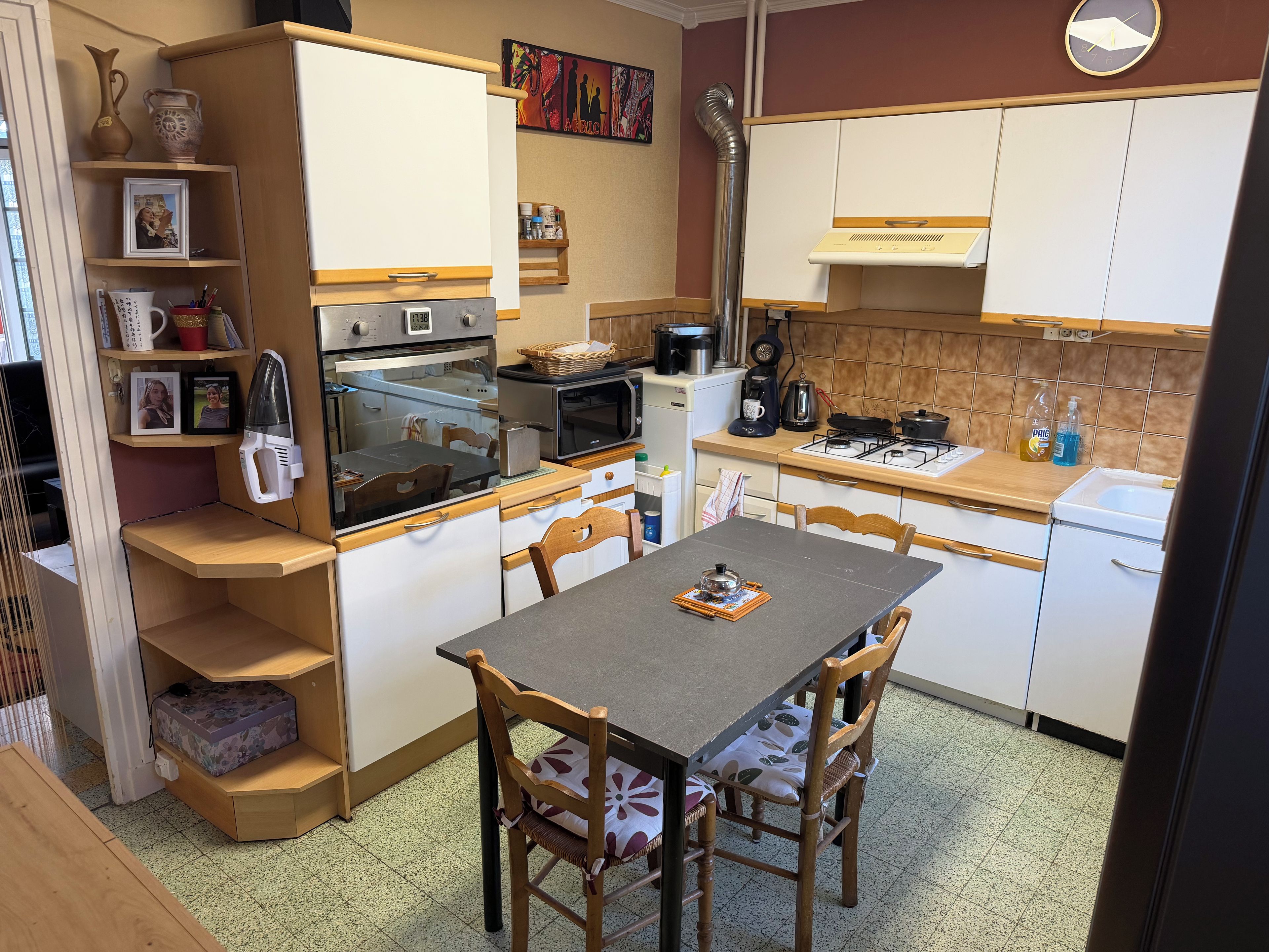 A compact kitchen with a dining table, chairs, and basic appliances.