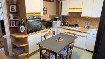 A compact kitchen with a dining table, chairs, and basic appliances.
