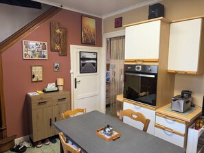 Una cucina compatta con forno a incasso, un piccolo frigorifero e un tavolo da pranzo in legno con sedie.