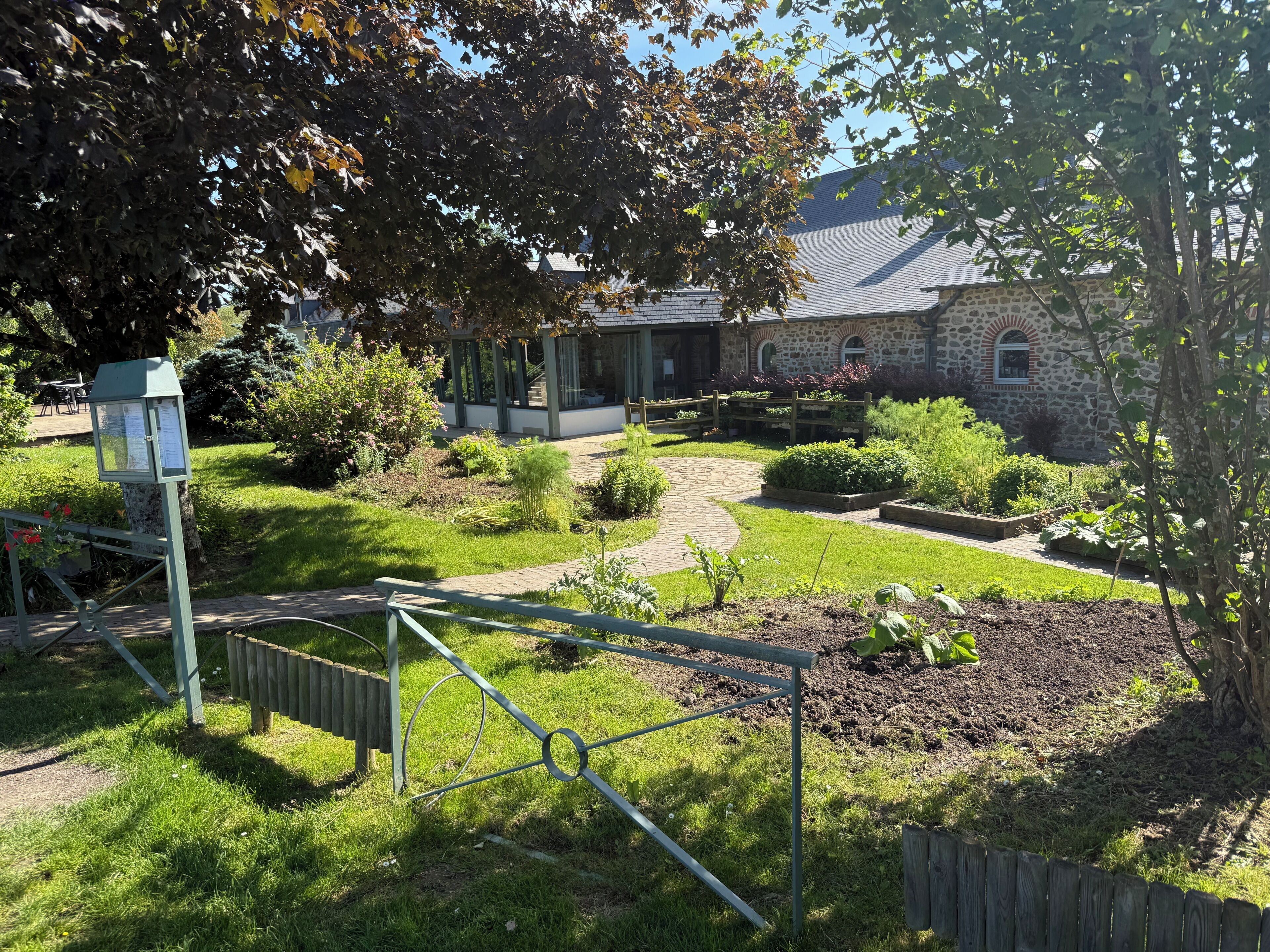Un jardin agrémenté d’un bâtiment en pierre, d’une clôture en métal et d’un chemin pavé.
