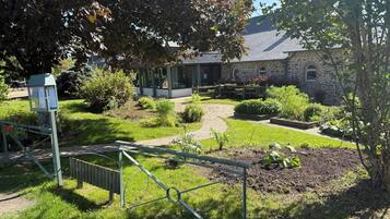 Un jardin agrémenté d’un bâtiment en pierre, d’une clôture en métal et d’un chemin pavé.