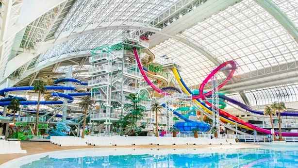 An indoor water park with multiple water slides and a large pool area.