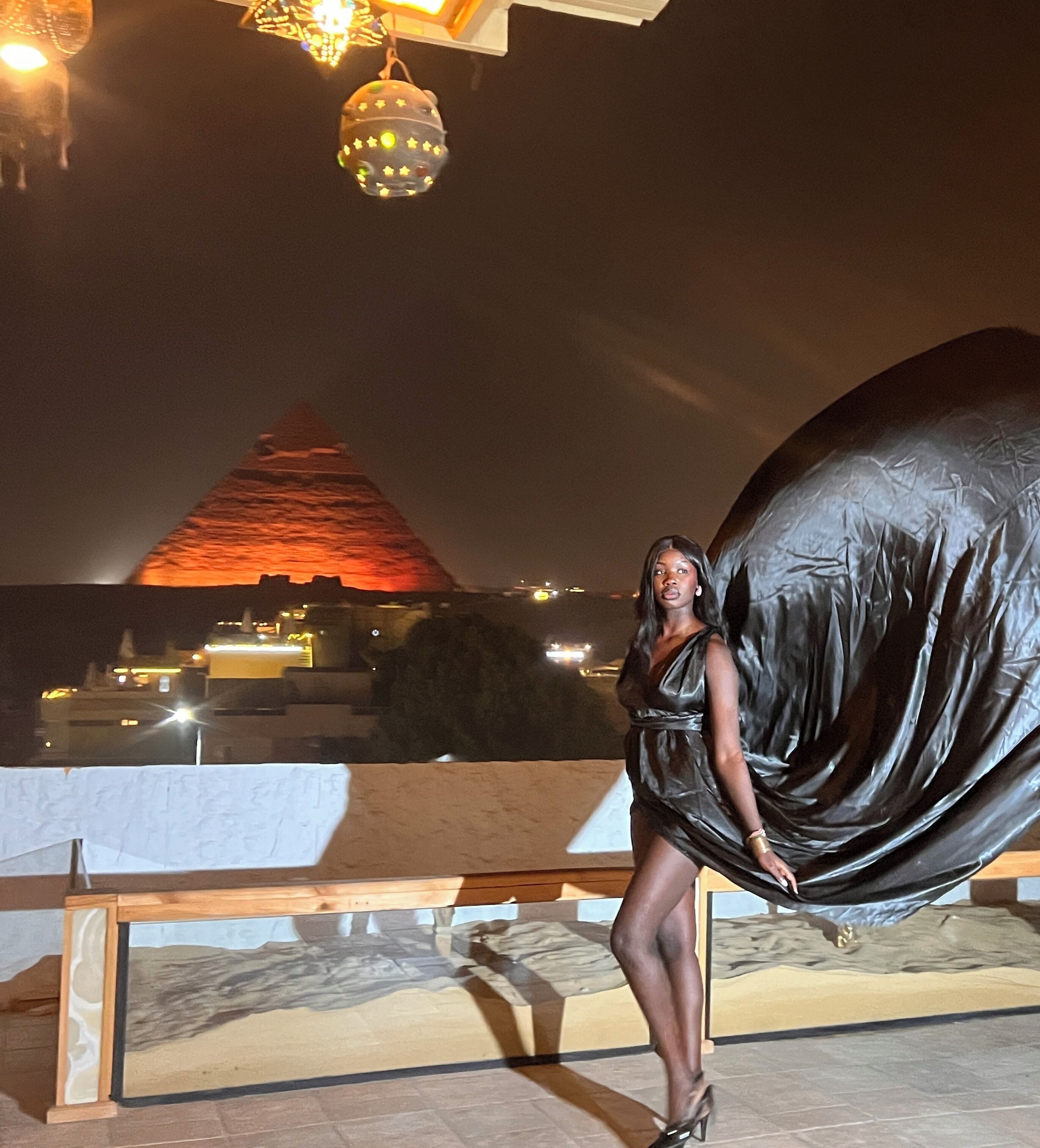 Una persona de pie frente a una escultura abstracta grande y negra.