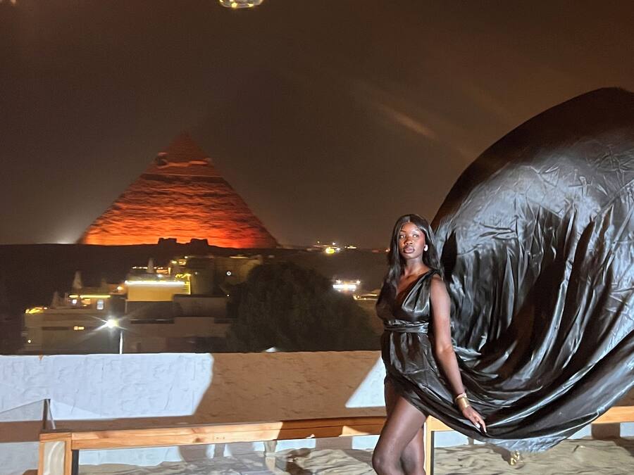 Una persona de pie frente a una escultura abstracta grande y negra.