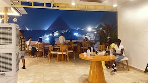 Ravintola, josta avautuu näkymä pyramidiin ja taustalla siintäviin kaupungin valoihin.