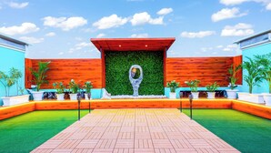 A courtyard with a central seating area, surrounded by potted plants and a wooden wall. - MyOtel - Santacruz (Mumbai)