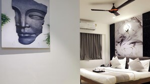 A modern bedroom with a bed, a ceiling fan, and a marble wall. - MyOtel - Santacruz (Mumbai)