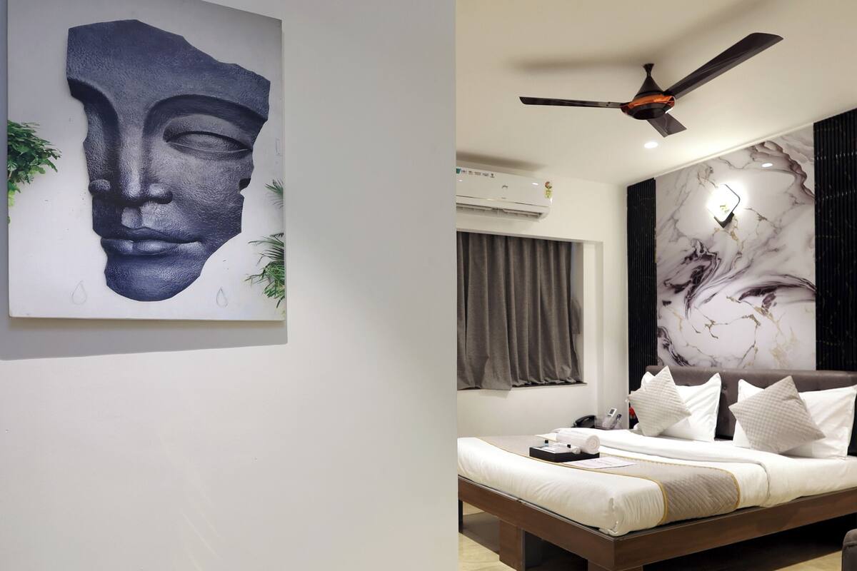 A modern bedroom with a bed, a ceiling fan, and a marble wall.