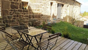 A stone building with a wooden deck and outdoor seating area.