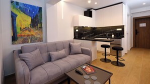 Un soggiorno moderno con un divano grigio, un tavolino da caffè e un quadro che raffigura una scena di strada.