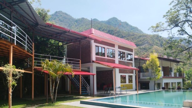 Un bâtiment à deux étages doté d’une piscine, entouré d’une pelouse et d’arbres.
