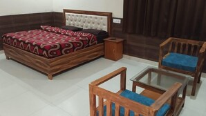 Une chambre à coucher comprenant un lit, une table de chevet, une chaise en bois et une table avec un plateau en verre.