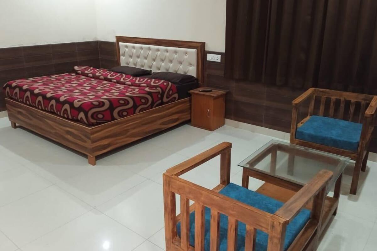 A bedroom with a bed, a nightstand, a wooden chair, and a glass-top table.