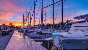 A marina with boats docked, a wooden walkway, and a clear sky. - Kokomo Floating Bungalow (Merritt Island)