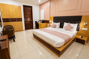 A modern bedroom with a large bed, wooden wardrobe, desk, and chair.