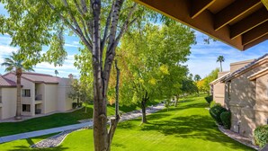 A well-maintained courtyard with a pathway, trees, and buildings with balconies. - Resort style condo in Scottsdale (Scottsdale)