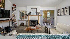 A modern living room with a fireplace, a sofa, a coffee table, and a bookshelf. - Resort style condo in Scottsdale (Scottsdale)
