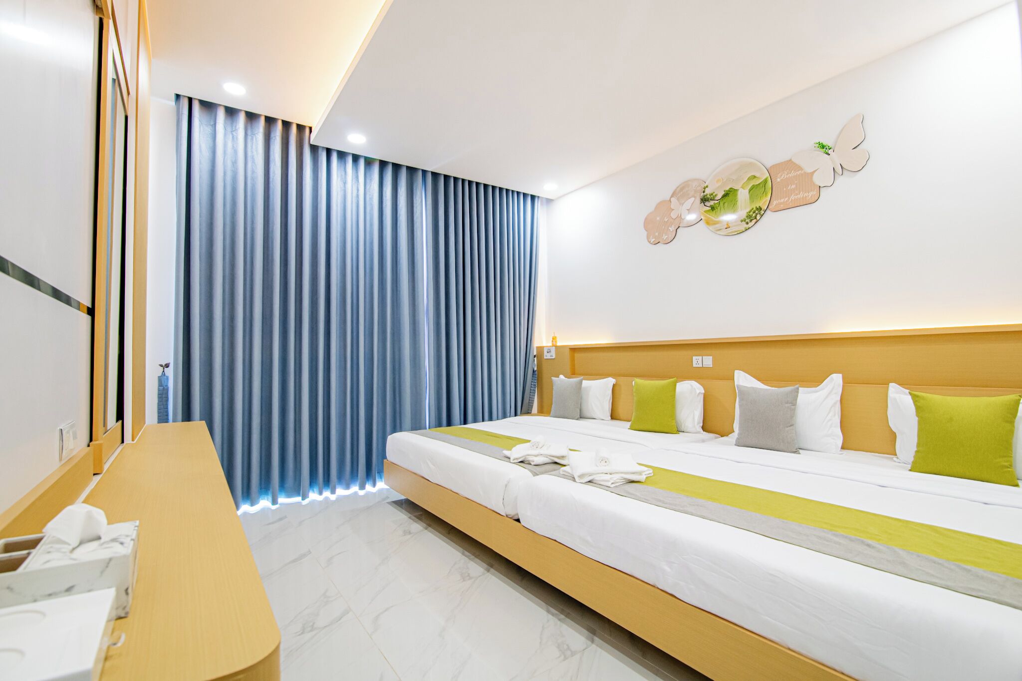 A hotel room with a large bed, a wooden desk, and a blue curtain.
