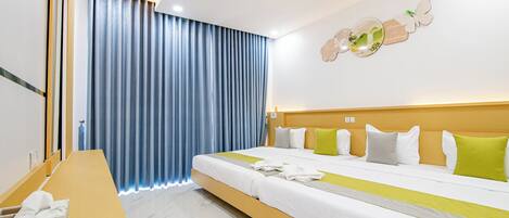 A hotel room with a large bed, a wooden desk, and a blue curtain.