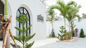 Een villa met een witte gevel, een groot rondboogvenster en een bordje met de tekst 'DEKT VILLA'.