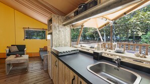 A compact kitchen with a sink, wooden cabinets, and a dining area with a bench. - Luxury Lodge for 5 people (Ghisonaccia)