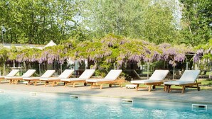 A poolside area with lounge chairs and a pergola covered with purple flowers. - Luxury Lodge for 5 people (Ghisonaccia)