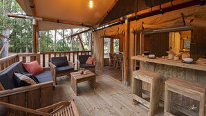 An outdoor wooden deck with a bar area, seating, and a view of trees. - Luxury Lodge for 5 people (Ghisonaccia)