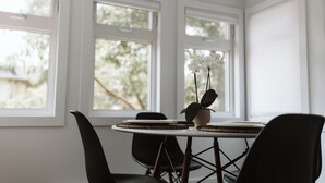 A dining area with a round table, black chairs, and a potted orchid. - Luxury Modern Apartment in Downtown Century Home - 2 Bedroom, Free parking x 4 (Peterborough)