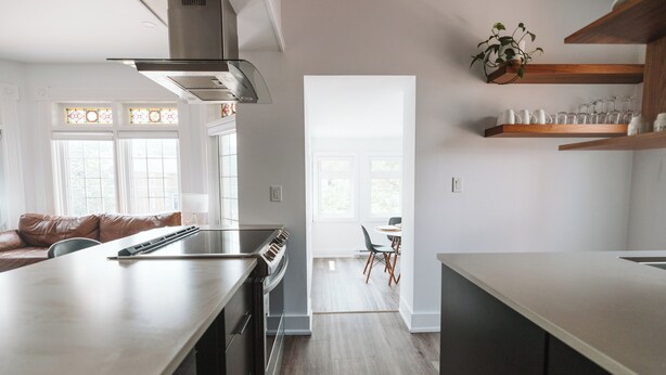 A modern kitchen with a central island, stainless steel appliances, and wooden flooring. - Luxury Modern Apartment in Downtown Century Home - 2 Bedroom, Free parking x 4 (Peterborough)