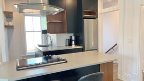 A modern kitchen with a central island, stainless steel appliances, and dark cabinetry. - Luxury Modern Apartment in Downtown Century Home - 2 Bedroom, Free parking x 4 (Peterborough)