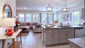 A spacious kitchen with a central island, a dining area with a sofa, and a large window providing natural light. - Beautiful 5 Bed Pool Home With Game Room-7543ol 5 Bedroom Home (Davenport)
