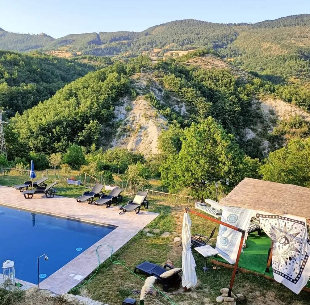 Un área de piscina con sillones de descanso y vistas a un paisaje montañoso.