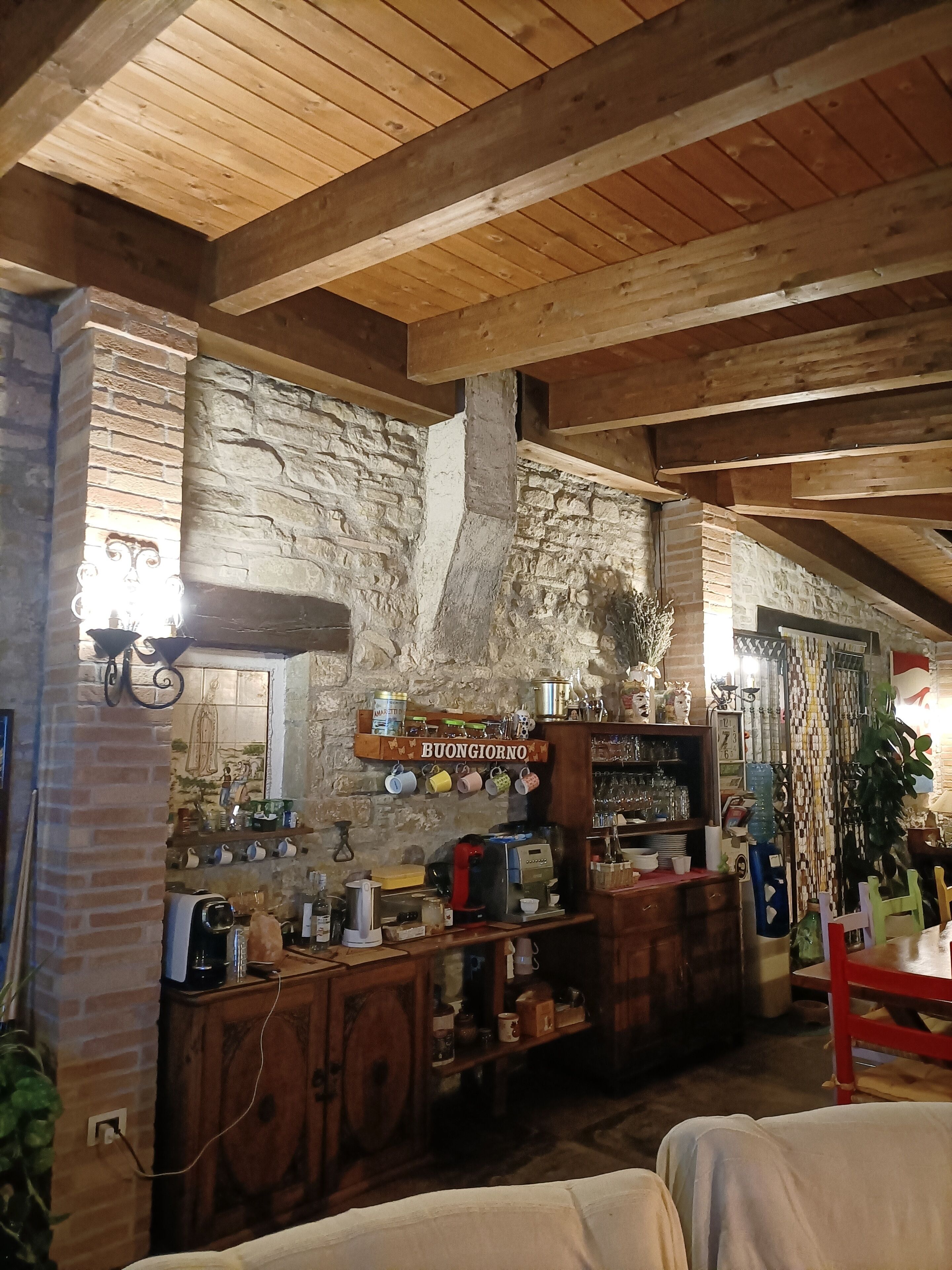Ein rustikaler Innenraum mit freiliegenden Holzbalken, einer Steinwand und einer Bar mit verschiedenen Gegenständen.
