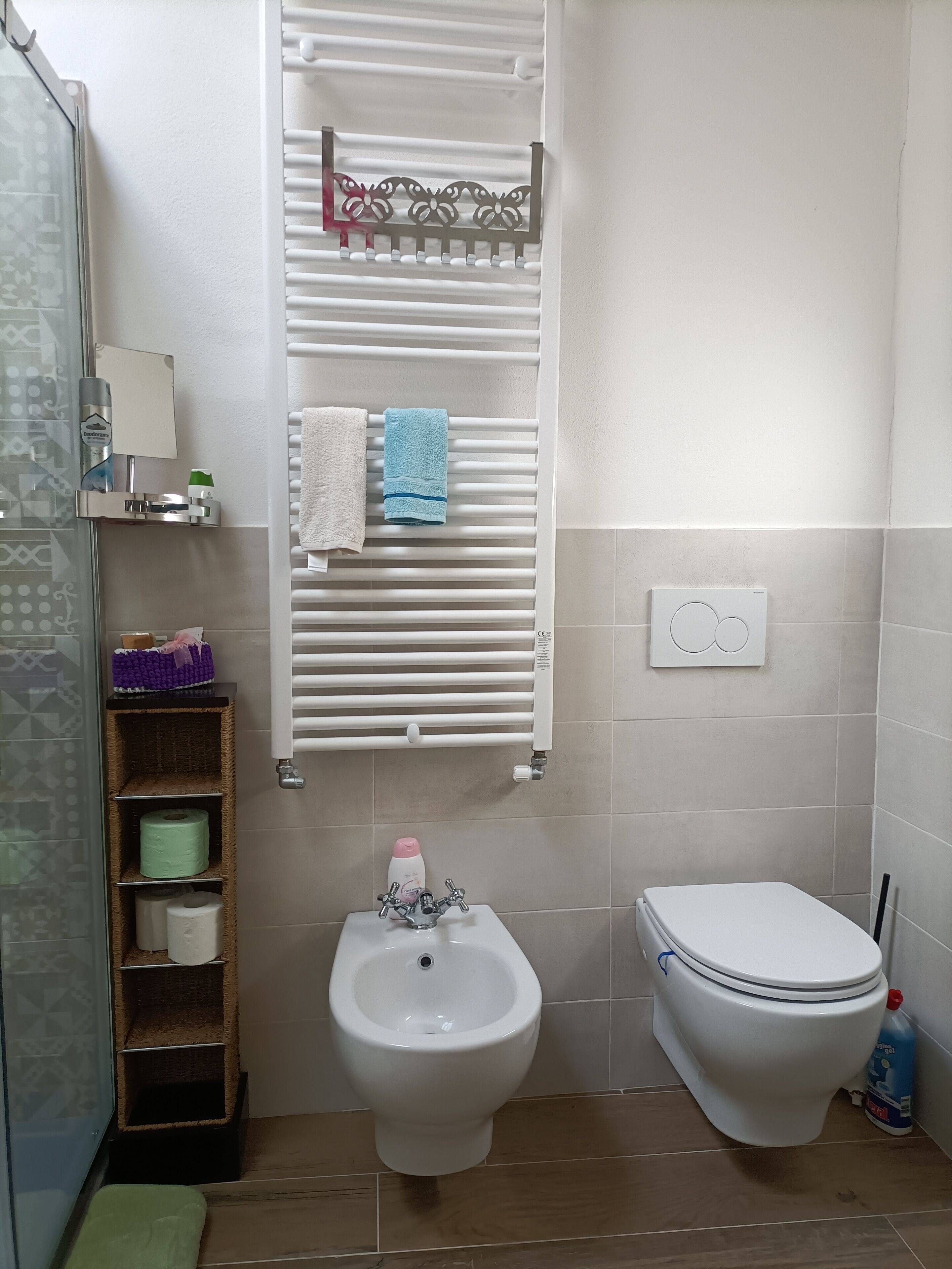 Ein Badezimmer mit integriertem Bidet, Toilette, Handtuchhalter und Ablagefläche für Toilettenartikel.