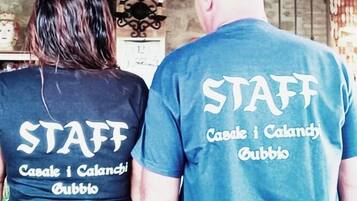 Two people wearing matching t-shirts with "STAFF" and "Casale i Calanchi Gubbio" printed on the back.