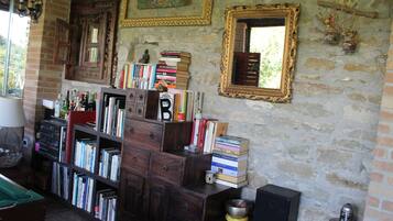 A room with a brick wall, wooden bookshelves, a mirror, and a small table with a bowl.