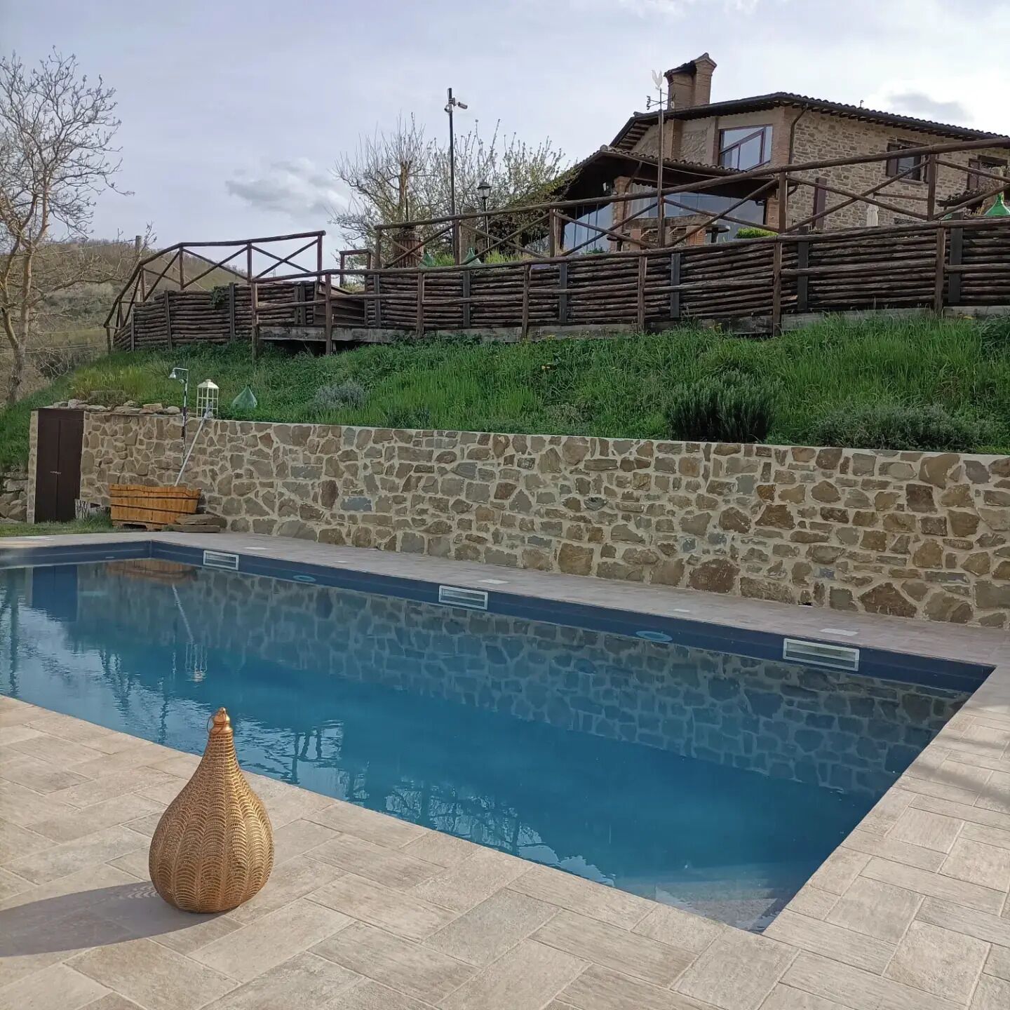 Una piscina con paredes de piedra y una terraza de madera.