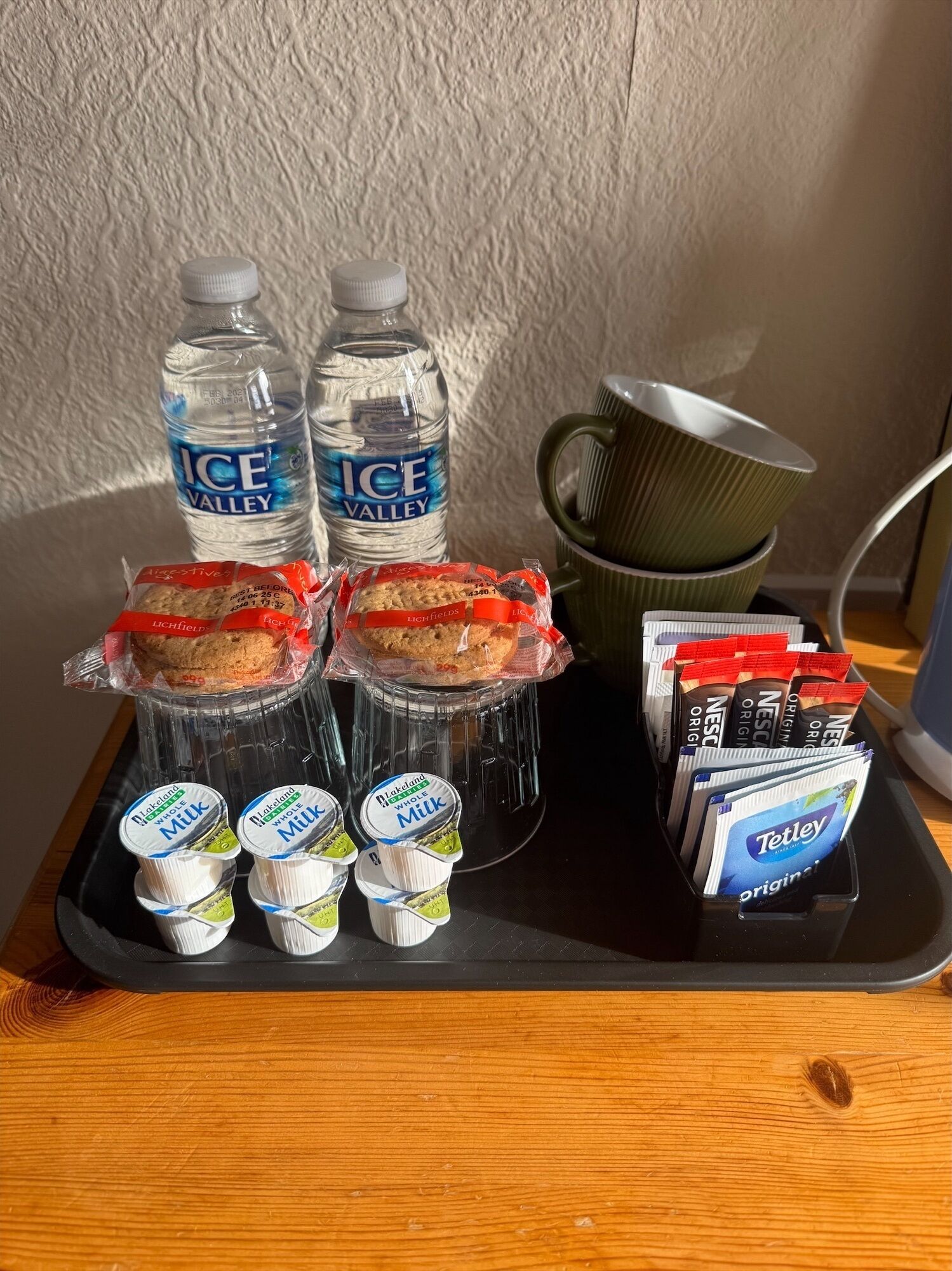 A tray with water bottles, packaged snacks, yogurt, and coffee pods.