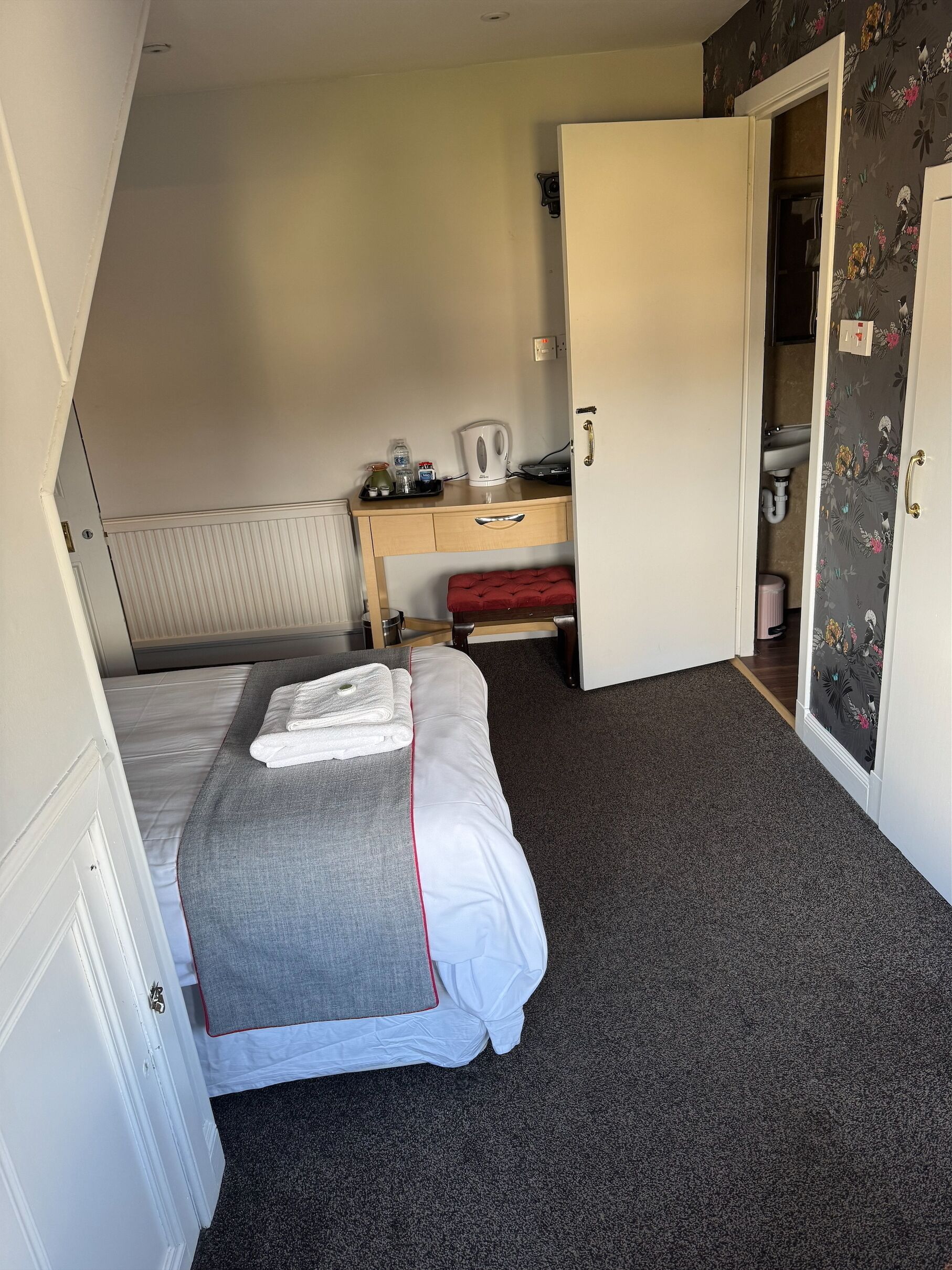 Un dormitorio con cama, escritorio, radiador y armario.