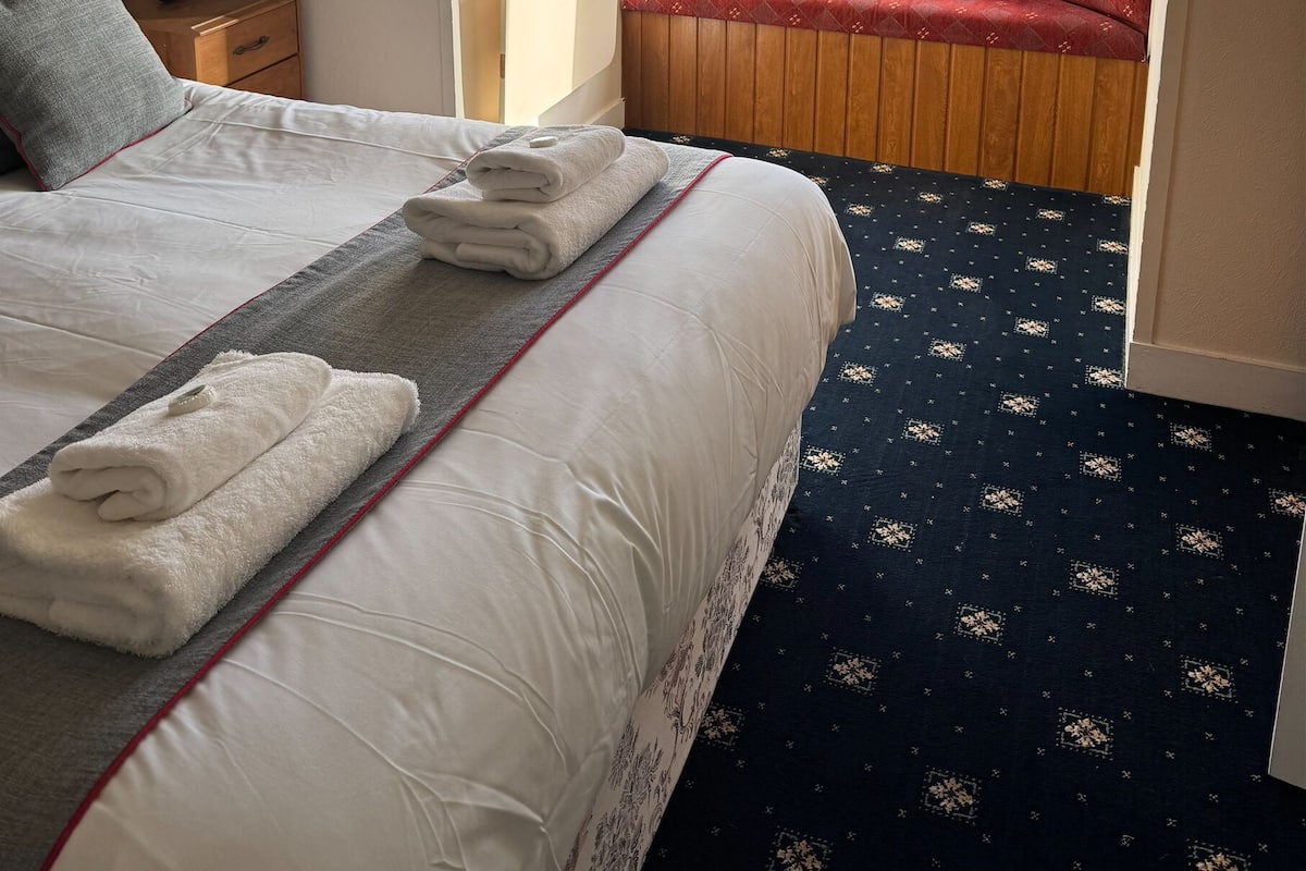 A hotel room with a large bed, a small seating area by the window, and a view of the outside.