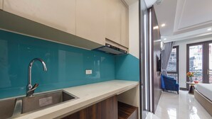 A modern kitchen with a built-in sink, wooden cabinets, and a teal backsplash. - Infinity HaNoi Hotel & Travel (Hanoi)