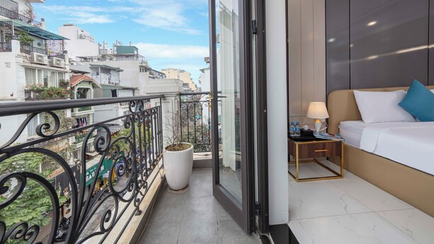 A balcony with a metal railing, a potted plant, and a view of the cityscape. - Infinity HaNoi Hotel & Travel (Hanoi)