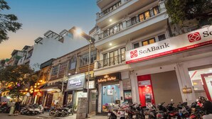 A street view with a bank, a restaurant, and parked scooters. - Infinity HaNoi Hotel & Travel (Hanoi)
