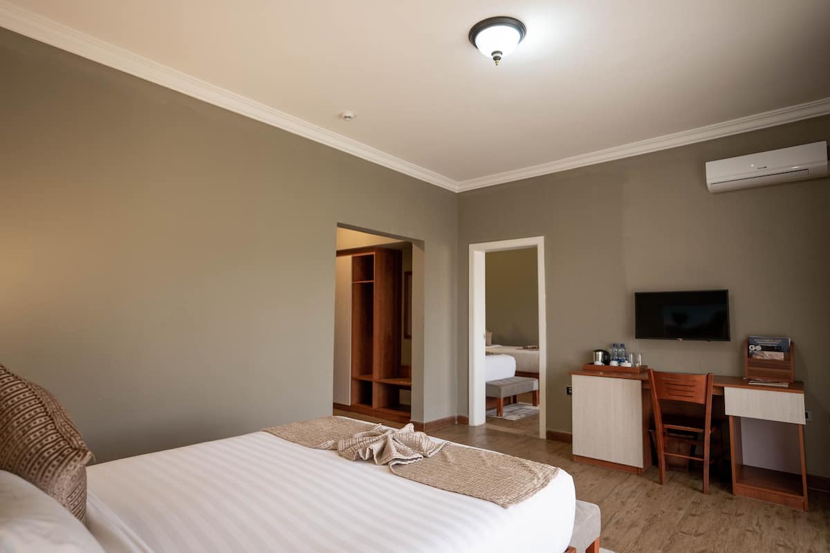 A hotel room with a bed, a desk, a chair, a TV, and a wardrobe.