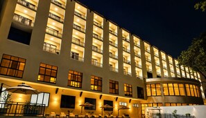 Een meerlaags hotel met balkons, een overdekt buitenzitgedeelte en een gebogen gevel.