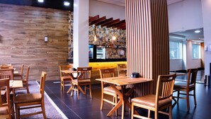 Een restaurantinterieur met houten tafels en stoelen, een bar met flessen en een houten wand.