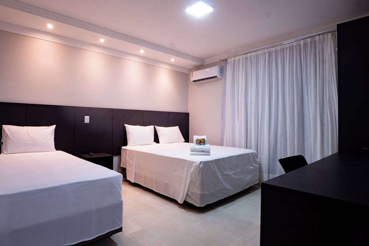 Une chambre d’hôtel avec deux lits, un bureau et une télévision.