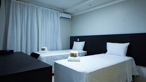 Een hotelkamer met twee enkele bedden, een bureau en een stoel.